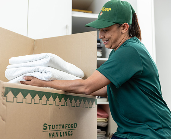 Stuttaford Van Lines team member professionally packing household belongings into a moving box for relocation.